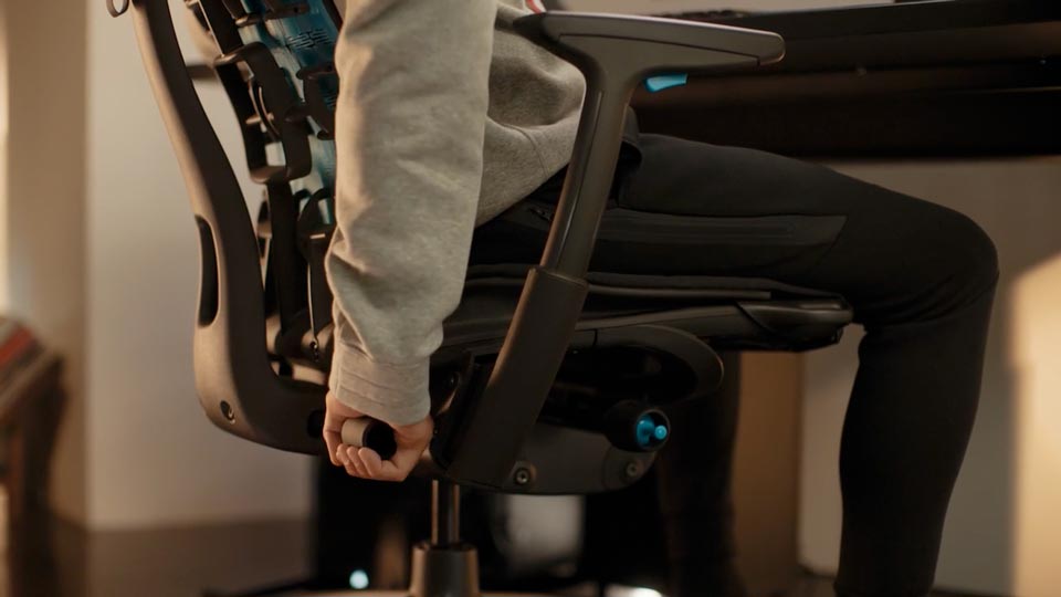 En närbild av en persons hand som justerar BackFit på en svart Embody Gaming Chair.