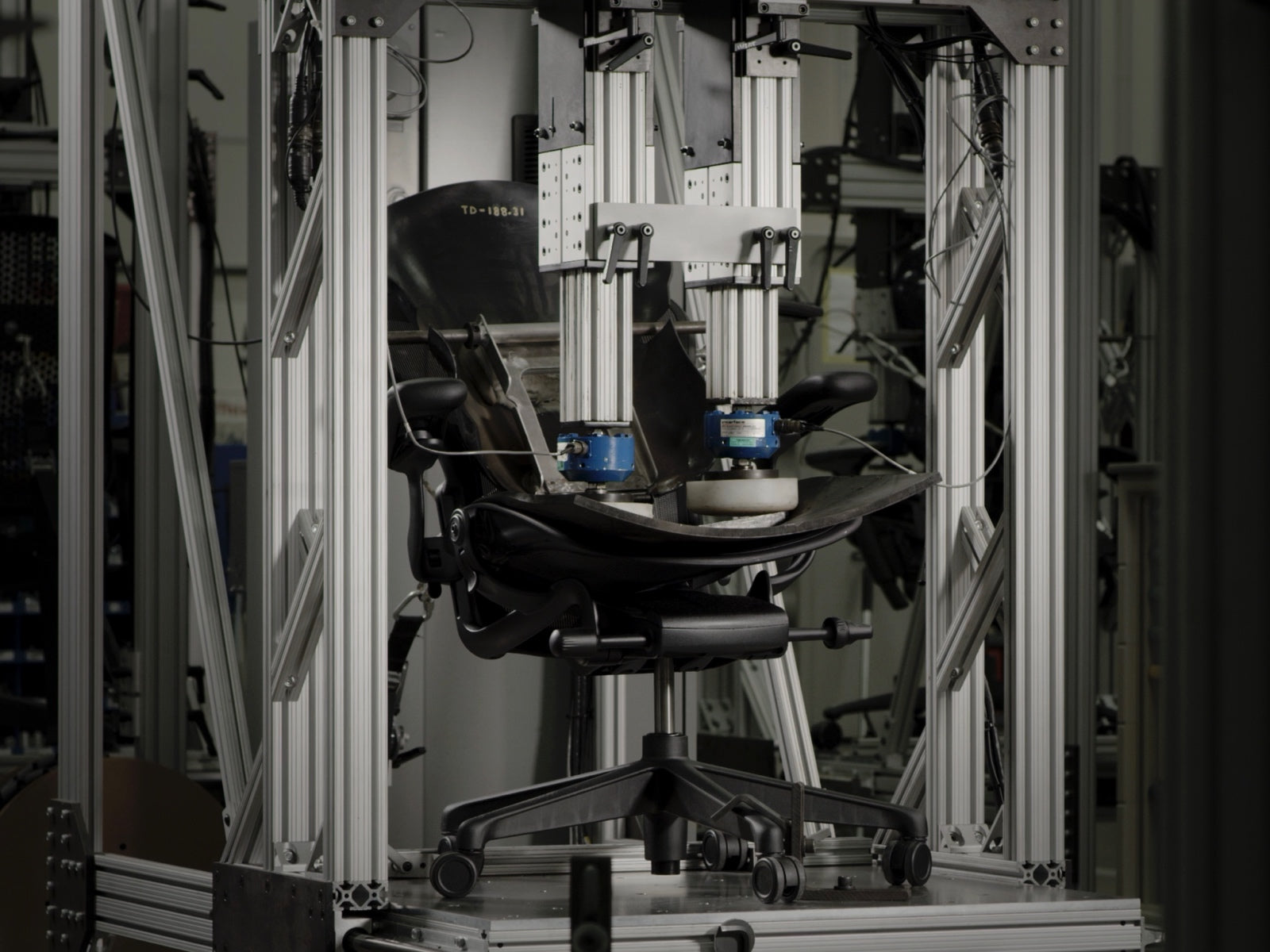 An Embody Gaming Chair, shown from the side, in a testing machine at the Herman Miller manufacturing site.